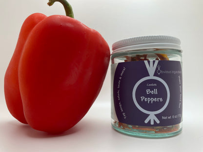 Red bell pepper leaning against jar of dried bell peppers with purple label