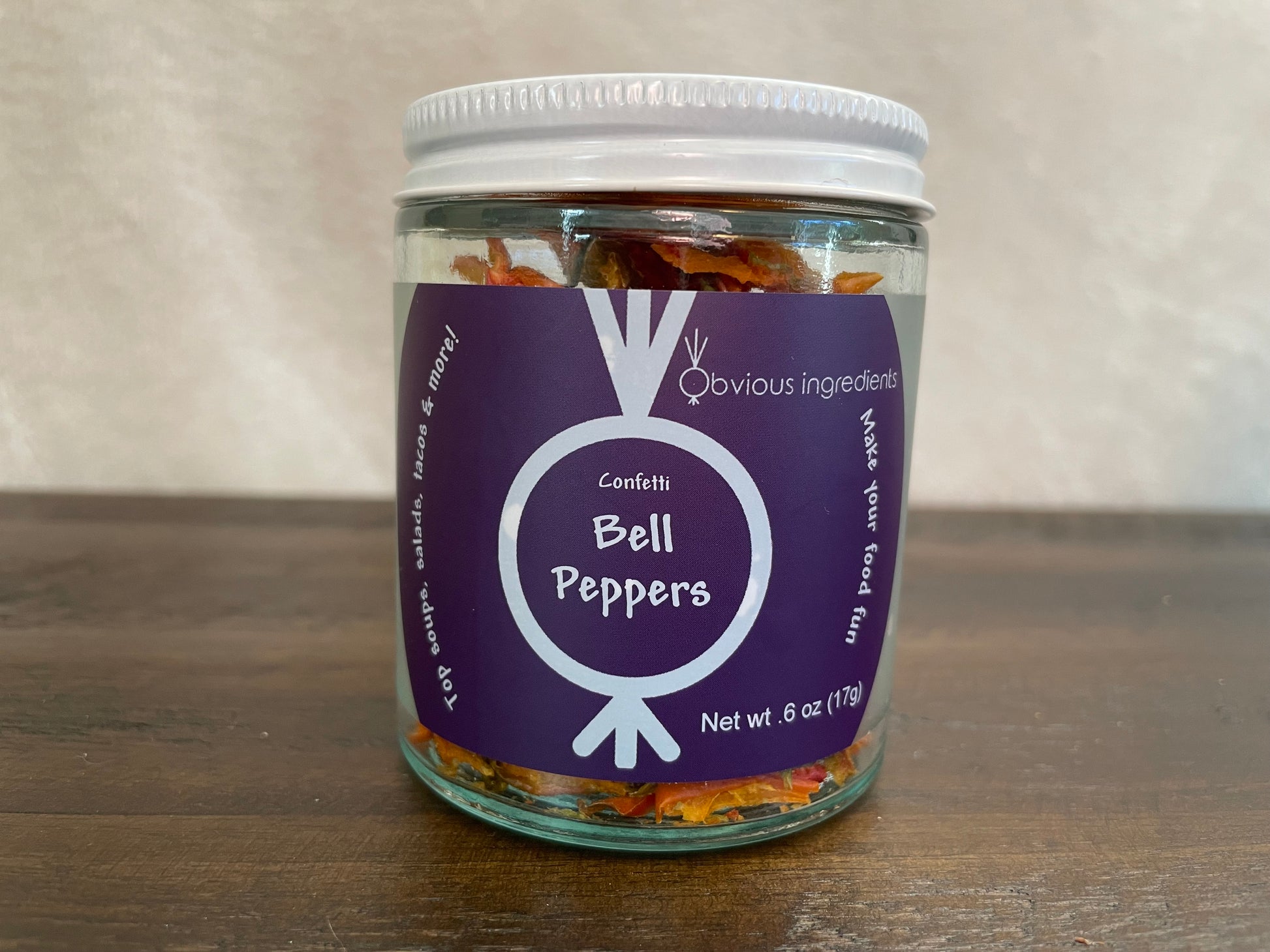 Jar of dried bell peppers with purple label on wood surface