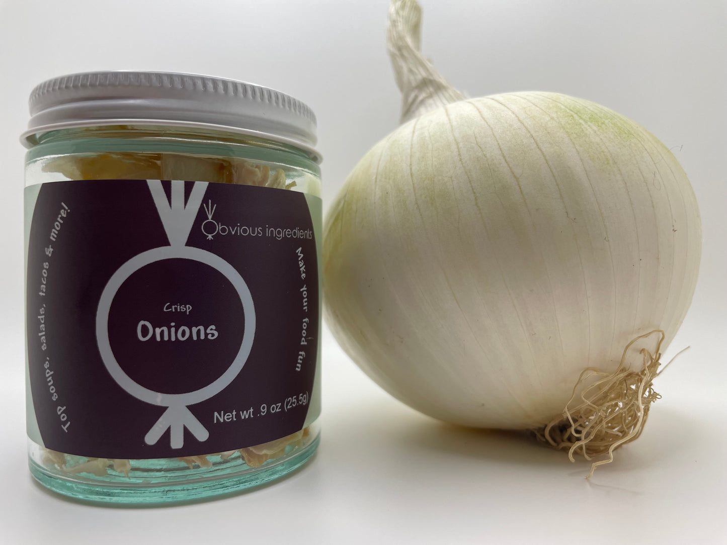 Jar of dehydrated chopped onions next to a fresh whole onion with white background