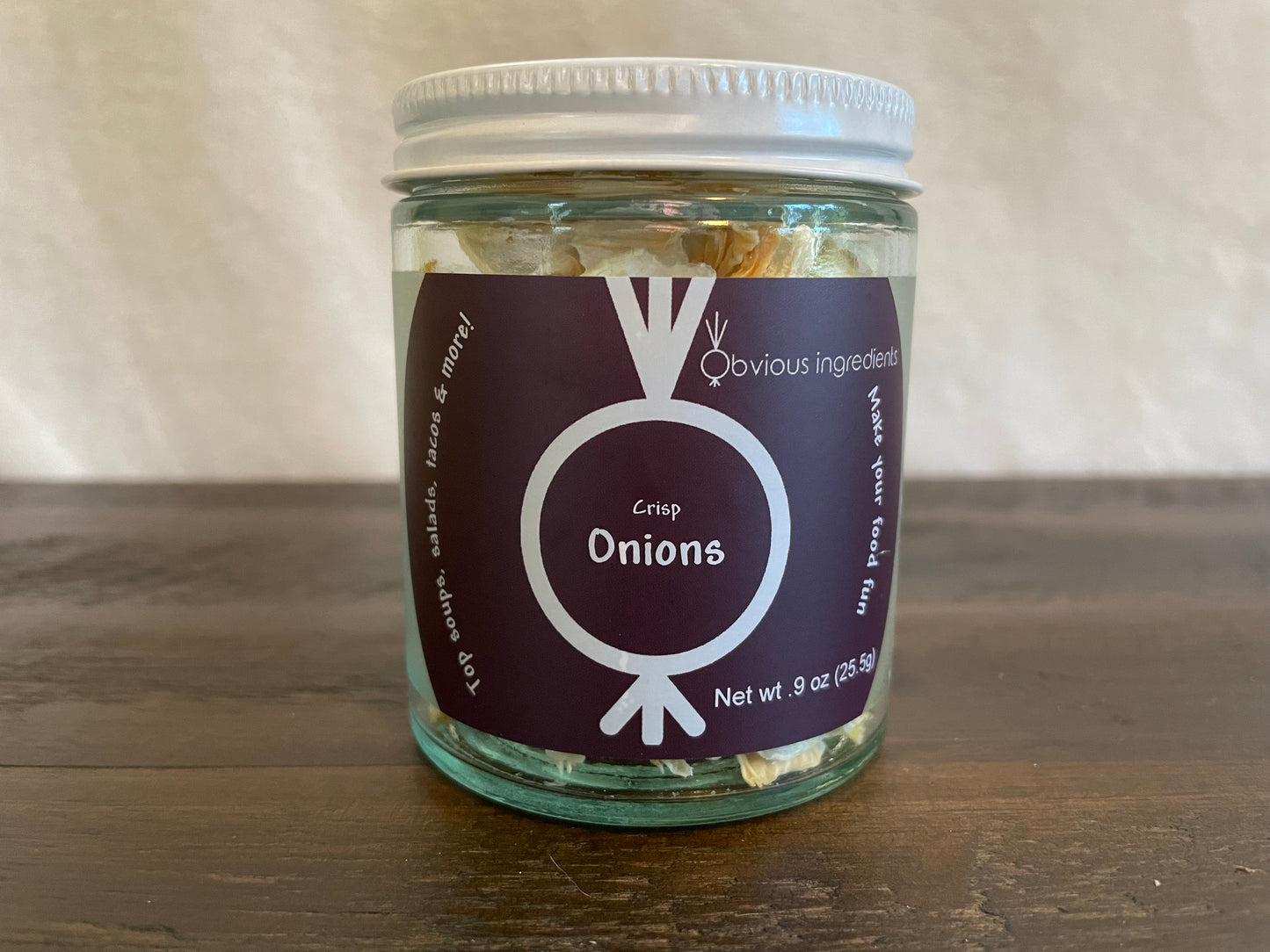 Jar of dehydrated onions with purple label on wood surface with off-white background